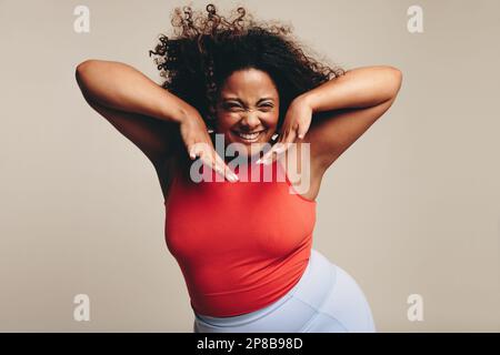 Femme excitée avec une forme ajustée et curviligne ayant un grand moment dans un entraînement de danse animé et expressif. Elle célèbre son corps, montrant fièrement son con Banque D'Images