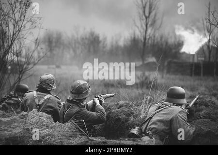 Les réacteurs ont armé des fusils et se sont habillés comme soldats allemands de l'infanterie Wehrmacht de la Seconde Guerre mondiale combattant de manière défésive dans le Trench. Position défensive. Bâtiment Banque D'Images