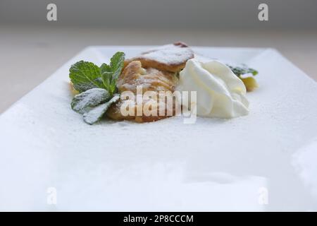 crème glacée dessert crêpes à la menthe arrosées de sucre en poudre à côté de crème fouettée sur une assiette carrée blanche pour le texte restaurant servant de délicieux repas offre spéciale Banque D'Images