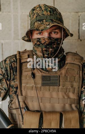 Un soldat en uniforme se tient devant un mur de pierre dans un équipement de guerre complet se préparant à la bataille Banque D'Images