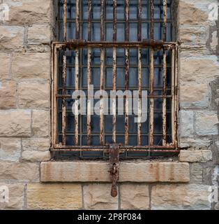 Une image rapprochée d'une petite fenêtre avec des barres métalliques rouillées sur l'ouverture Banque D'Images