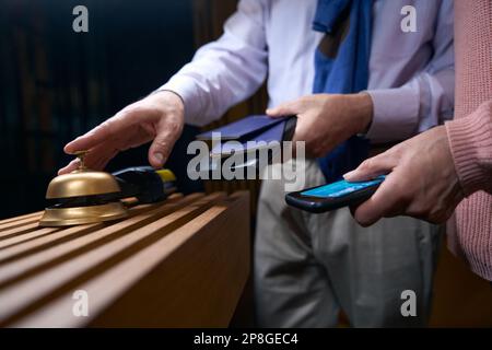 Un homme en vêtements de voyage appelle le personnel de l'hôtel pour s'inscrire Banque D'Images