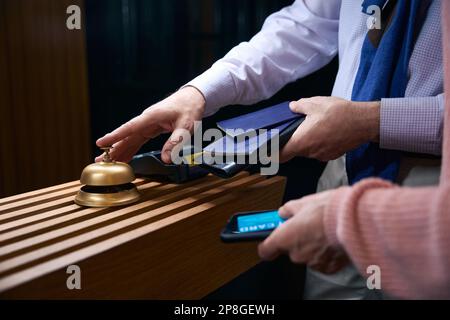 Un homme avec un passeport entre ses mains appelle le personnel de l'hôtel pour l'inscription Banque D'Images