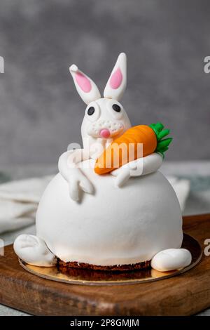 Gâteau spécialement conçu en forme de lapin. Gâteau sur table en bois gris et lapin de Pâques Banque D'Images