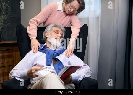 Le grand-père barbu s'est endormi dans un fauteuil confortable avec un livre Banque D'Images