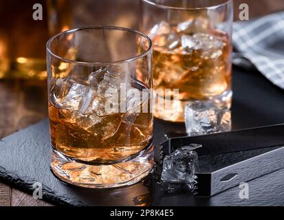 Deux verres de whisky avec glace sur un tableau noir en ardoise avec fond en bois Banque D'Images