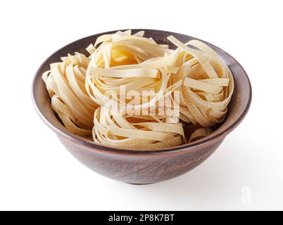 Pâtes tagliatelles non cuites dans un bol en céramique isolé sur fond blanc avec passe-cheveux Banque D'Images