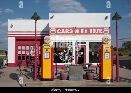 Une station-service avec deux pompes à carburant colorées au premier plan Banque D'Images