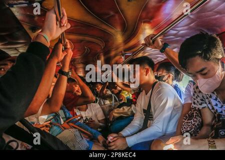 Les passagers sont assis à l'intérieur d'un jeepney de transport traditionnel. Depuis des décennies, les navetteurs se sont appuyés sur les jeepneys, une méthode de transport dynamique et emblématique aux Philippines. Elle est considérée comme une représentation emblématique du transport philippin et est devenue un symbole national. Les premières jeepneys ont été transformées en jeeps militaires américains abandonnés aux Philippines après la Seconde Guerre mondiale en véhicules de transport public uniques pouvant accueillir jusqu'à 20 passagers. Au cours de sa décennie, le gouvernement fait pression sur une initiative de modernisation pour remplacer la jeepney dépassée Banque D'Images