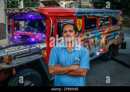 Mark se tient à côté de son jeepney traditionnel et pose pour la caméra dans le métro de Manille. Depuis des décennies, les navetteurs se sont appuyés sur les jeepneys, une méthode de transport dynamique et emblématique aux Philippines. Elle est considérée comme une représentation emblématique du transport philippin et est devenue un symbole national. Les premières jeepneys ont été transformées en jeeps militaires américains abandonnés aux Philippines après la Seconde Guerre mondiale en véhicules de transport public uniques pouvant accueillir jusqu'à 20 passagers. À l'approche de sa décennie, le gouvernement fait pression sur une initiative de modernisation pour la remplacer Banque D'Images