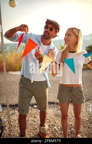jeune adulte couple caucasien utilisant des petits drapeaux colorés en forme de triangles pour la décoration Banque D'Images