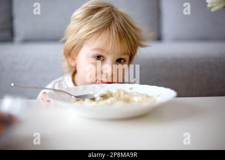 Mignon petit garçon, manger des pâtes avec du fromage blanc à la maison pour le déjeuner Banque D'Images