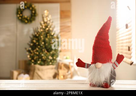 Gnome de Noël drôle sur table en bois blanc dans la chambre avec des décorations de fête. Espace pour le texte Banque D'Images