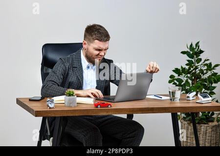 homme assis sur une chaise à la table et reposant, à l'aide d'un ordinateur portable Banque D'Images