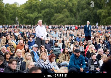 Les gens regardent la couverture télévisée du jour funéraire de la reine Elizabeth II sur un grand écran à Hyde Park, Londres. Banque D'Images