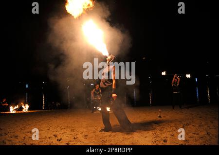 Homme reniflard de feu et femmes jongleurs de feu se présentant la nuit sur la plage de sable. 11 novembre 2019. Kiev, Ukraine Banque D'Images