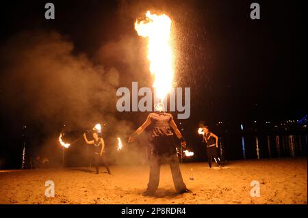 Homme reniflard de feu et femmes jongleurs de feu se présentant la nuit sur la plage de sable. 11 novembre 2019. Kiev, Ukraine Banque D'Images