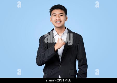 Un jeune homme d'affaires asiatique séduisant se réjouit de célébrer le succès isolé sur fond bleu clair Banque D'Images