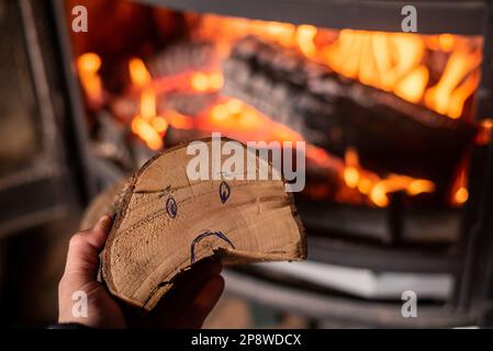 Augmentation du prix du bois de chauffage concept. La main tient le journal avec une smiley triste contre le fond de foyer en feu Banque D'Images