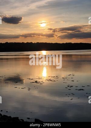 Un beau coucher de soleil orange chaud sur le lac tranquille Banque D'Images
