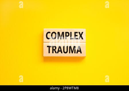 Symbole de traumatisme complexe. Concept mots trauma complexe sur bloc de bois. Magnifique table jaune fond jaune. Psychologie des affaires complexe trauma conc Banque D'Images