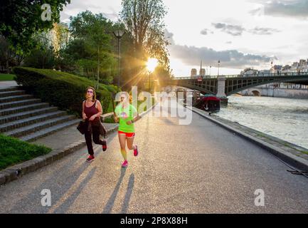 15-05-2016 Paris, France. 2 filles courent sur la Seine Dr Mai - coucher de soleil orange! Notre Dôme au loin en 6th districtof Paris Banque D'Images