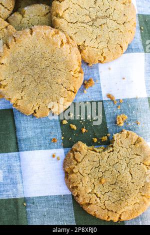 Gros plan sur une pile de biscuits au beurre d'arachide fraîchement cuits avec une bouchée et de la chapelure sur la nappe Vichy. Banque D'Images