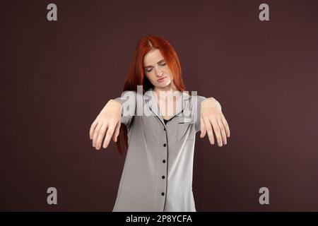 Jeune femme portant un pyjama en état de sommeil sur fond marron Banque D'Images