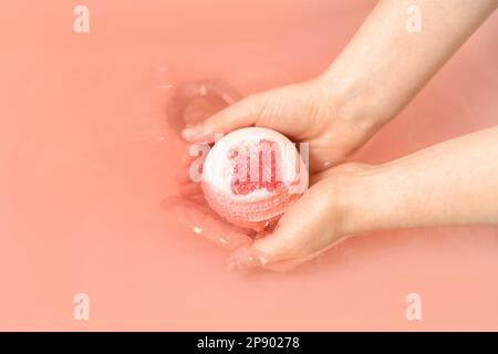 Femme mettant la bombe de bain dans l'eau dans la chambre, gros plan Banque D'Images