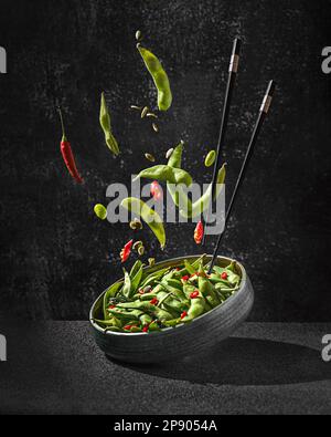 salade de haricots edamame dans des gousses au piment sur fond noir Banque D'Images