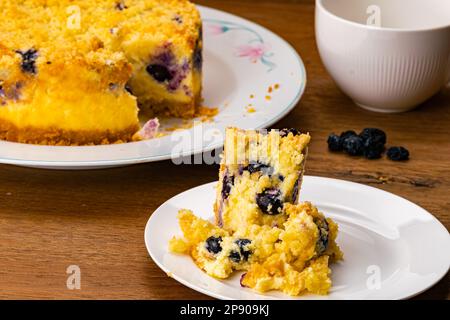 Morceau de délicieux cheesecake maison aux myrtilles dans un plat en céramique blanche avec l'ensemble dans une plaque en céramique et une tasse de café sur tabl en bois Banque D'Images