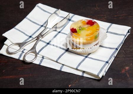 Gâteau avec gelée, kiwi, cerises et mangue sur table. Mini dessert délicieux sur fond de bois, en gros plan Banque D'Images