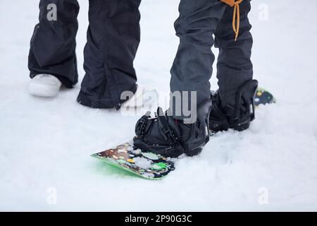 Gros plan sur les jambes d'un snowboarder et d'un instructeur. Un homme aide un novice snowboarder à rester sur la pente. Entraînement au snowboard Banque D'Images