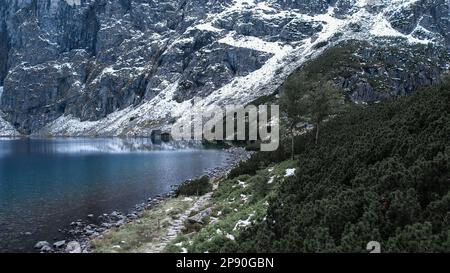 Czarny Staw Pod Rysamy ou lac Black Pond près de la cabane de montagne Morskie Oko Snowy dans les montagnes polonaises de Tatry, vue sur les drones, Zakopane, Pologne. Vue aérienne prise de magnifiques collines verdoyantes et montagnes dans des nuages sombres et reflet sur le lac Morskie Oko. Destination touristique de voyage Banque D'Images