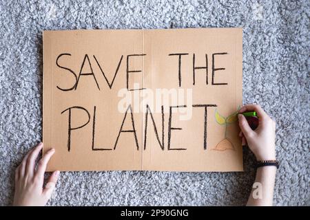 Une militante écrivant l'affiche « SAVE THE PLANET » pour manifestation contre le réchauffement planétaire et la pollution de la terre. Banderole en carton pour protester contre le changement climatique. Banque D'Images