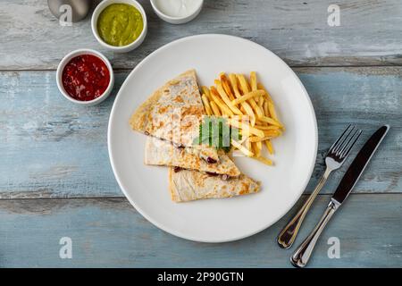 Quesadilla mexicaine avec sauce et frites sur une assiette en porcelaine blanche Banque D'Images