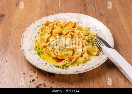 Pamppardelles avec filet de poulet, ail et piment arrosé de parmesan et de persil haché, gros plan. Le plat est servi avec des couverts Banque D'Images