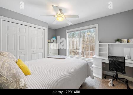 Cette chambre blanche confortable dispose d''un lit bien fait et de grandes fenêtres Banque D'Images