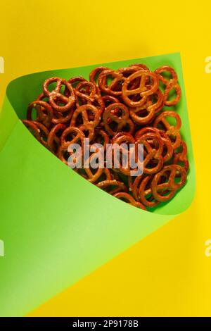 Gros plan des mini-bretzels en papier vert clair cône se trouve sur fond jaune. Concept lumineux de l'Octoberfest Banque D'Images