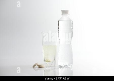 Le comprimé effervescent se dissout dans un verre d'eau. Verre avec médecine soluble sur fond blanc. Banque D'Images