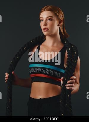 Il est absolument inutile de faire des excuses. Photo en studio d'une jeune femme sportive posant avec une corde de combat sur un fond noir. Banque D'Images