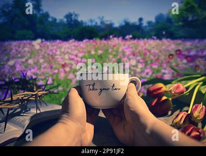 Homme tenant une tasse de thé. Bruit de fond du ressort. Couronne d'épines sur la Bible ouverte Banque D'Images