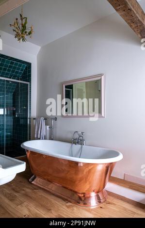 Baignoire sur pied en laiton avec miroir et douche dans la ferme Tudor du 16th siècle, Suffolk, Royaume-Uni. Banque D'Images