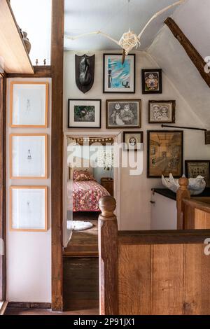 Œuvres d'art encadrées sur le palier avec banister en bois dans la ferme Tudor du 16th siècle, Suffolk, Royaume-Uni. Banque D'Images