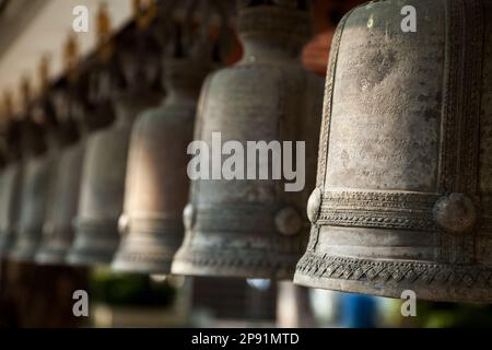 Rangée de cloches religieuses dans un sanctuaire bouddhiste. Cloche ornementale de bronze de monastère asiatique à un temple en Thaïlande Banque D'Images