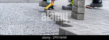 pose de pavés à interverrouillage pendant la construction de trottoirs et de routes. bannière avec espace de copie Banque D'Images