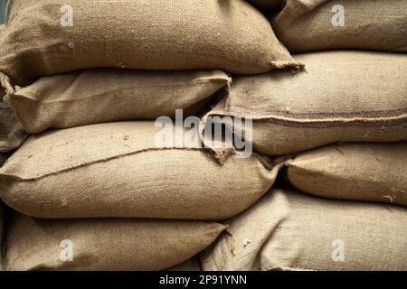 Pile de sacs de toile brune avec grain à un entrepôt. Gros tas de sacs de chanvre plein de récolte le stockage dans une exploitation agricole Banque D'Images