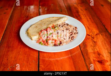 Plat Gallopinto avec quesillo et pico de gallo sur table en bois. Repas Gallo Pinto traditionnel avec Pico de Gallo et quesillo servis Banque D'Images