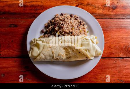 Vue de dessus du pinto gallo traditionnel avec Quesillo servi sur une table en bois. Assiette de galopinto nicaraguayen avec quesillo sur la table. typique Banque D'Images