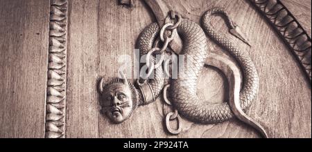 Symbole serpent de diable. Créature magique fantaisie sur une vieille porte, Abbaye du 12th siècle, Italie Banque D'Images